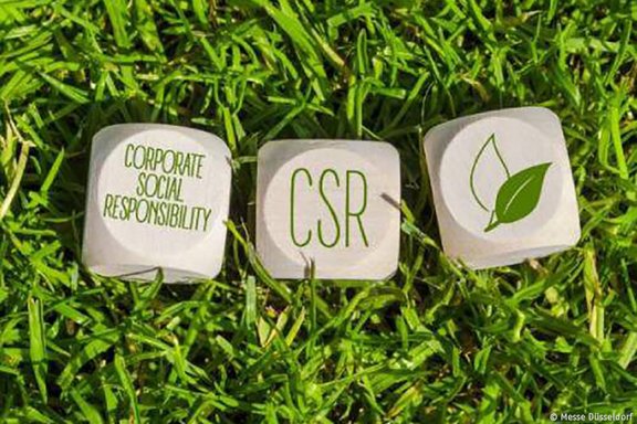 Corporate Social Responsibility (CSR) Würfel auf grünem Gras als Symbol für nachhaltige Verantwortung der Messe Düsseldorf.